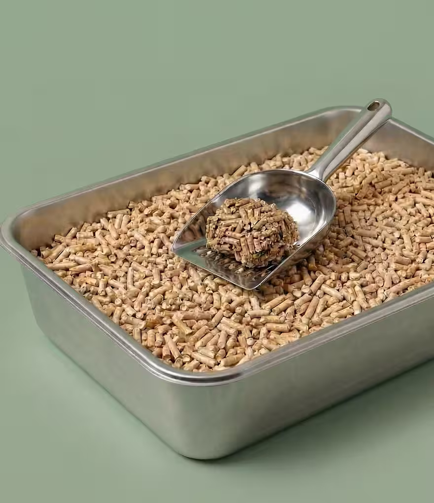 Metal litter box filled with pellet litter and a scoop resting on top